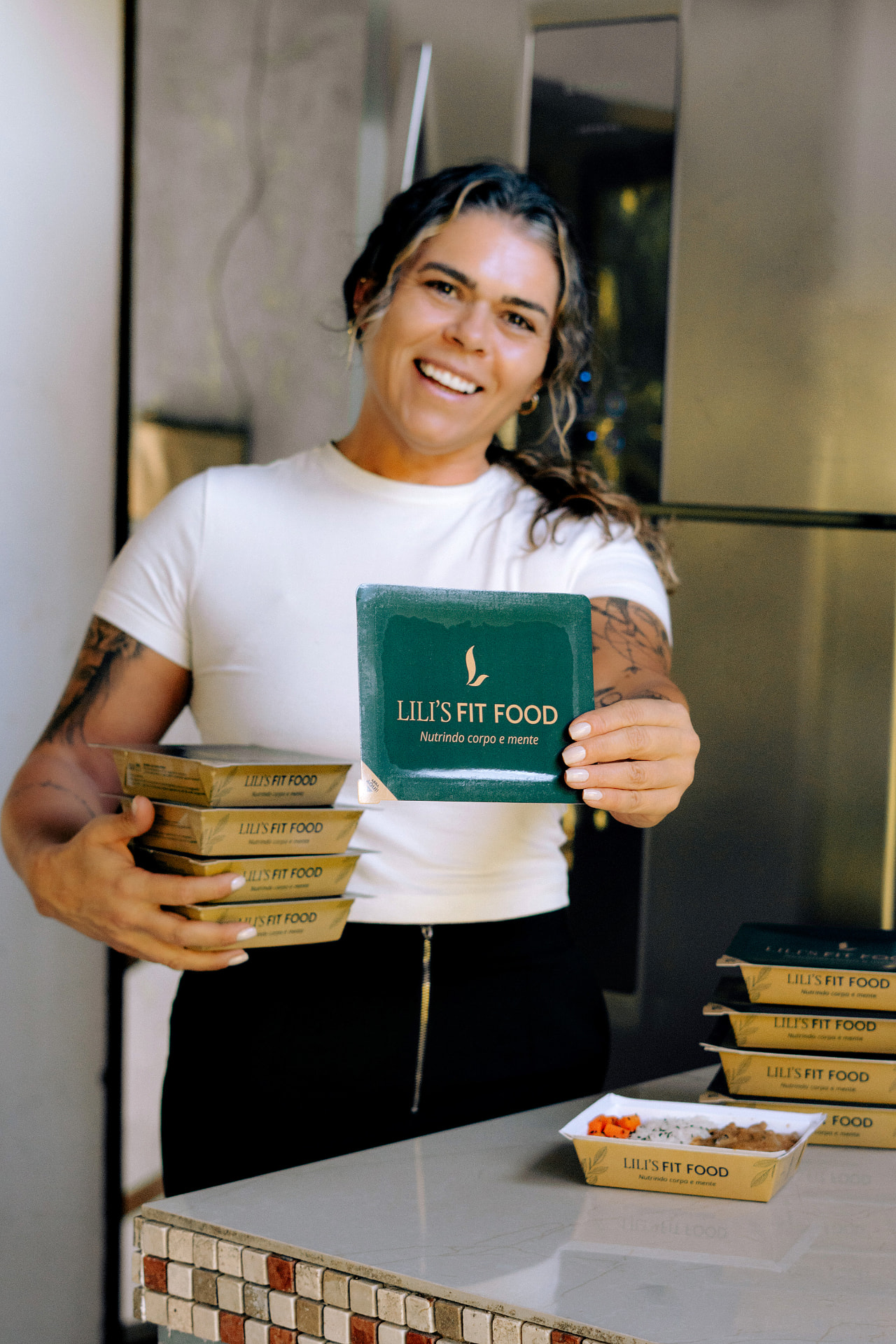 Lili, fundadora da LILI'S FIT FOOD, com as refeições da marca